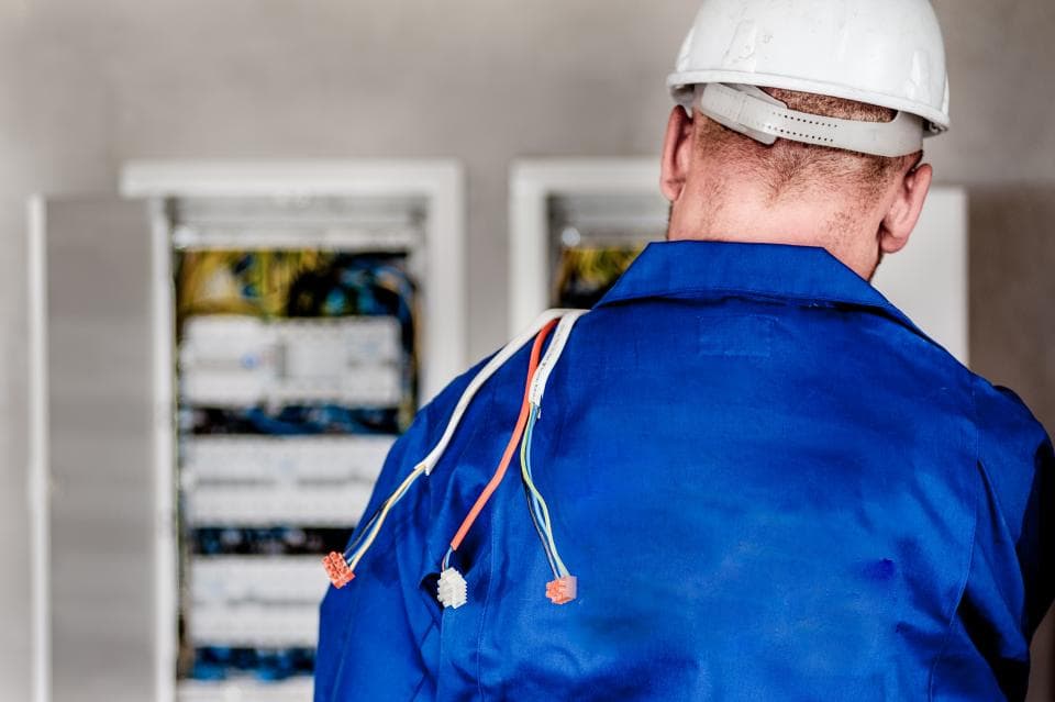 Field engineer in safety gear working on an electrical distribution panel